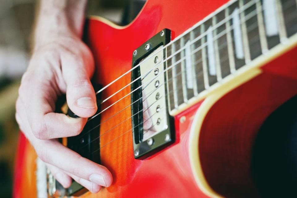 Gra kostką na czerwonej gitarze elektrycznej